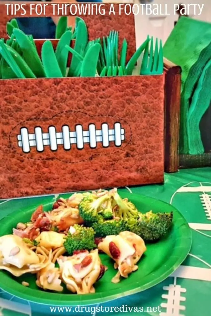 A football-shaped utensil holder, green utensils, green napkins, food on a green plate, all on a table with a football tablecloth on it and the words, "Tips For Throwing A Football Party" digitally written on top.