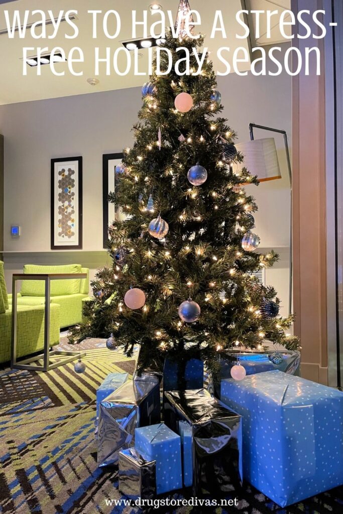 A Christmas tree and gifts on display in a hotel lobby with the words "Ways To Have A Stress-Free Holiday Season" digitally written on top.