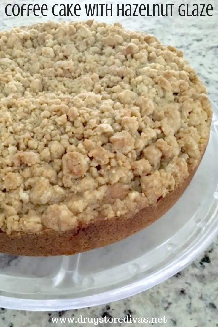 A coffee cake with a crumble topping on a cake stand with the words 
