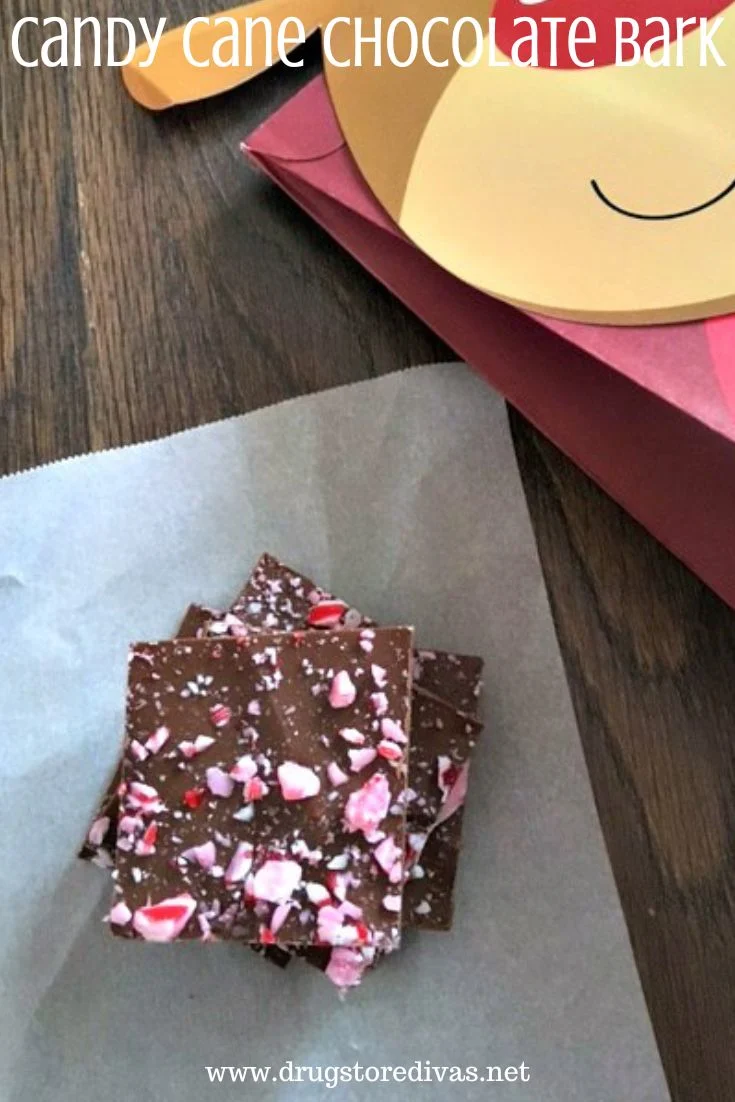 Pieces of candy cane chocolate bark on a piece of parchment paper next to a reindeer shaped bag with the words 