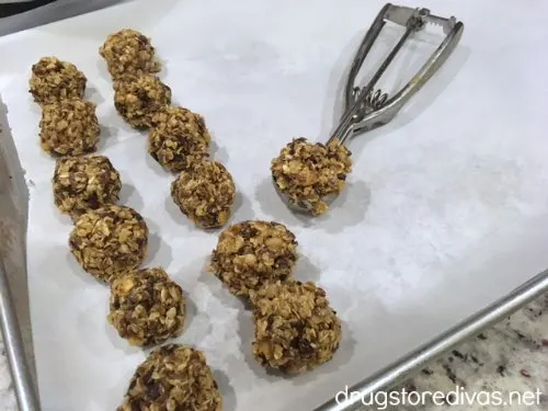 Energy balls on a pan with a cookie scoop on the side.