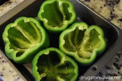 Green bell peppers sliced open in a pan.