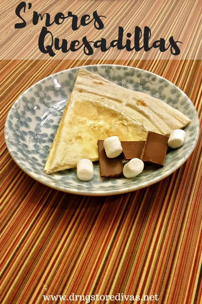 A quesadilla on a plate with chocolate and marshmallows and the words "S'mores Quesadillas" digitally written on top.