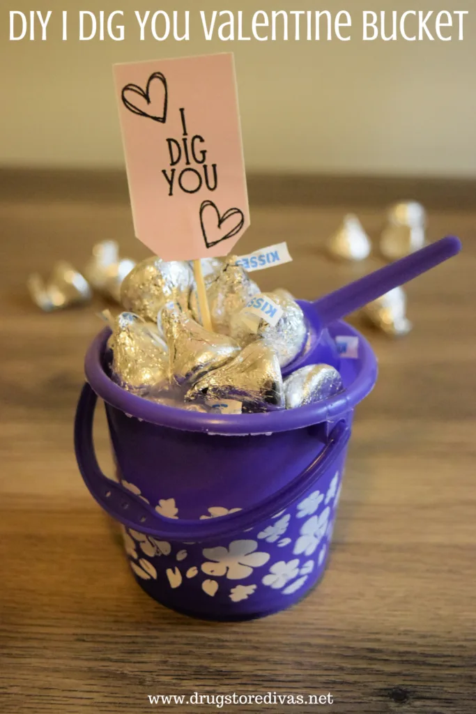 A purple bucket filled with Hershey's Kisses with a tag that says I Dig You sticking out and the words "DIY I Dig You Valentine Bucket" digitally written on top.