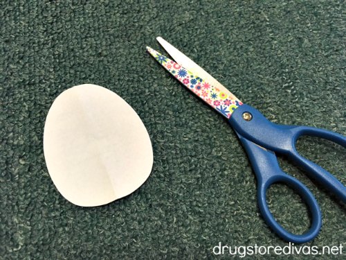 Scissors next to a white paper egg.