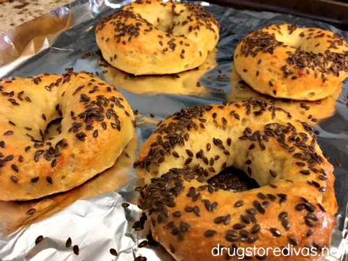 Homemade flax seed bagels on a baking sheet.