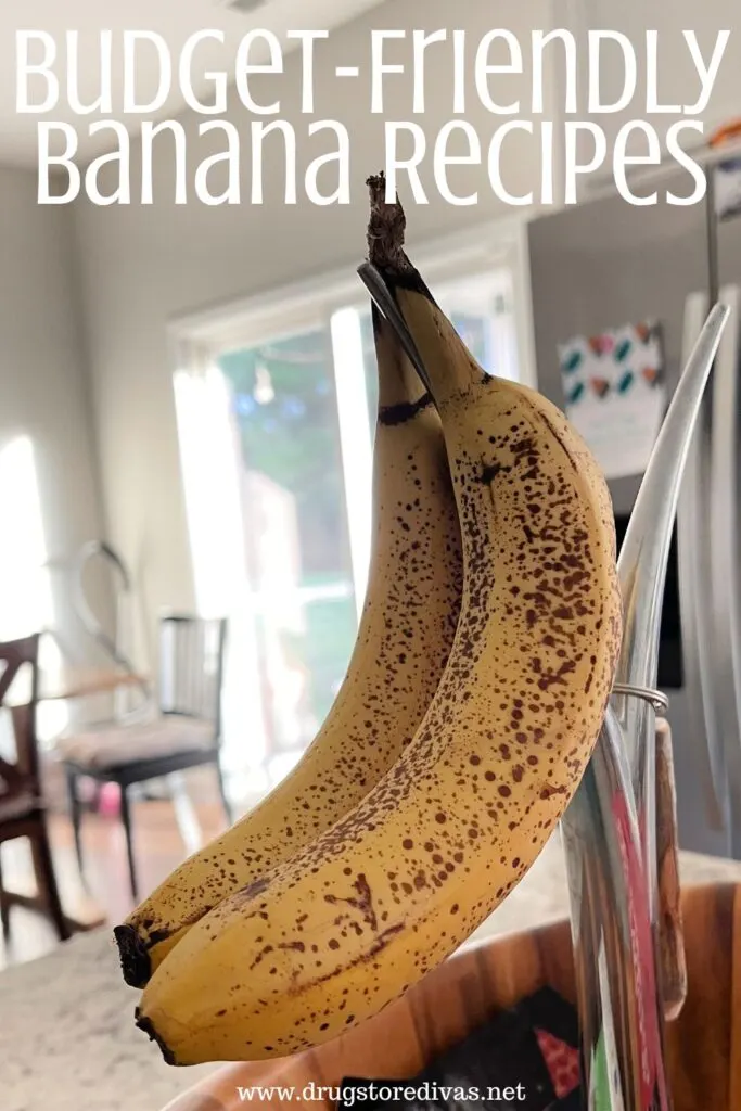 Bananas hanging in a fruit bowl in a kitchen.