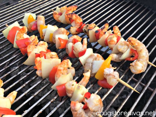 Four shrimp, pepper, and onion skewers on a charcoal grill.