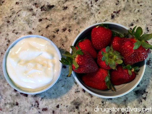 Yogurt in a bowl next to strawberries in a bowl.