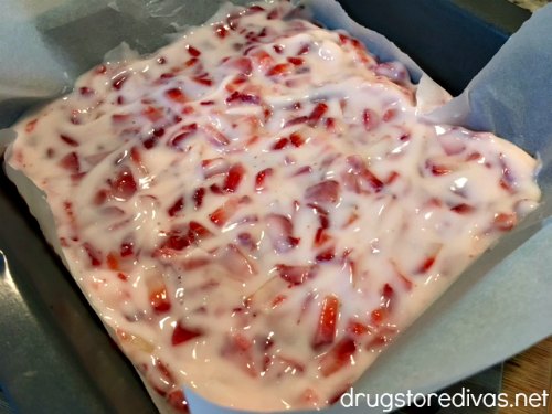 A yogurt and strawberry mixture in a pan with parchment paper.