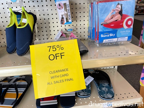 Random summer items on a shelf with a large yellow clearance sign advertising 75% off in front.