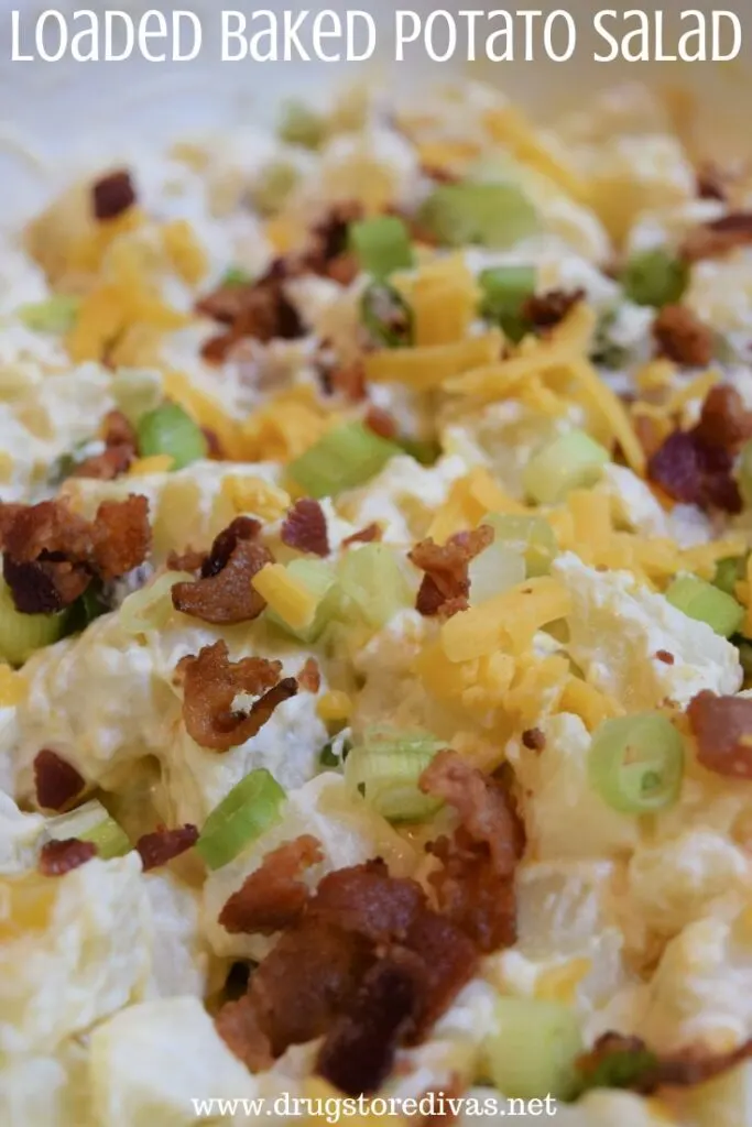 Potato salad with cheese, bacon, and chives in a bowl with the words "Loaded Potato Salad" digitally written on top.