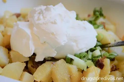 Sour cream on top of loaded potato cubes.