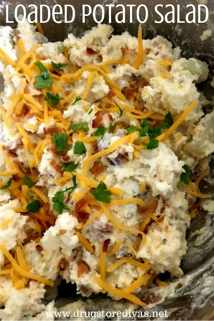 Potato salad with cheese, bacon, and chives in a bowl with the words 