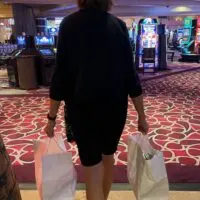 Woman carrying two shopping bags through the casino with the words 