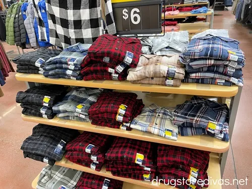 Three shelves of plaid shirts with a $6 price tag above them in a local Walmart.