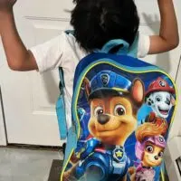 A little boy wearing a backpack with the words 