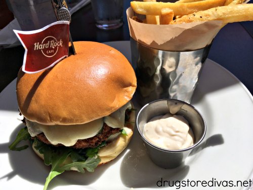 A burger, with a Hard Rock Cafe flag in it, and fries on a plate.