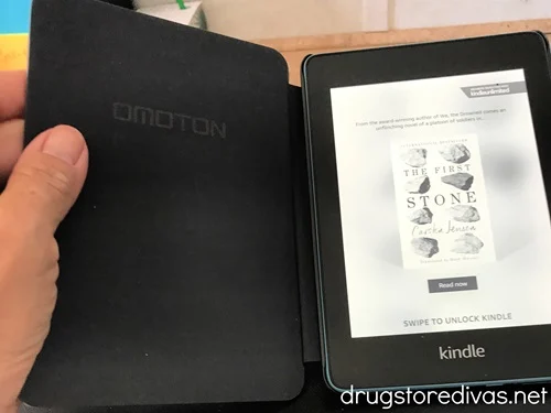 A hand holding open a Kindle device.