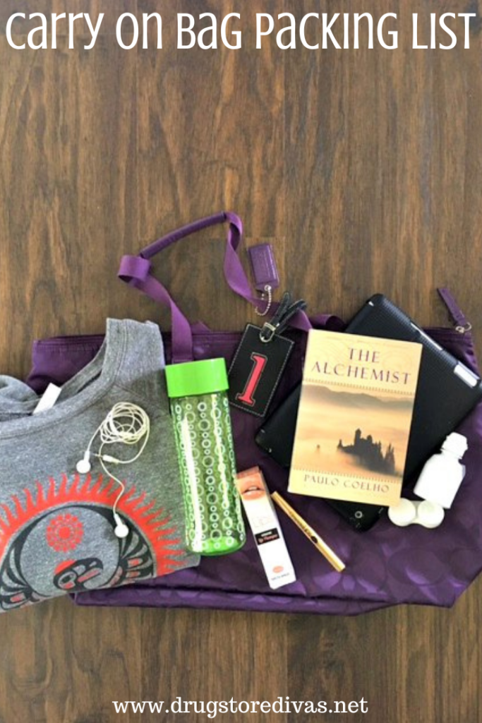 A purple bag with a sweatshirt, headphones, water bottle, makeup, book, and contact solution on it with the words "Carry On Bag Packing List" digitally written above it.