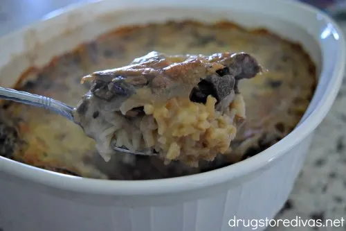 A spoonful of Mushroom Casserole above the casserole pan.