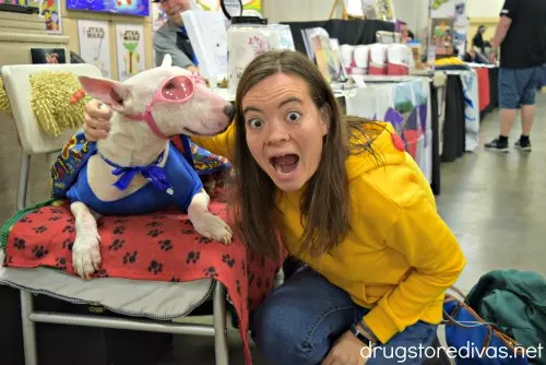 A girl posing with a super hero dog.