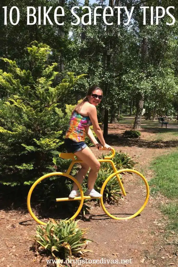 A woman riding a fake yellow bike in a park with the words "10 Bike Safety Tips" digitally written above her.