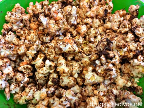 Popcorn in a bowl, covered with melted orange candy melts and melted chocolate chips.