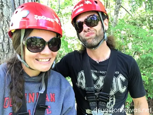 A man and a woman outside wearing red helmets and black sunglasses.