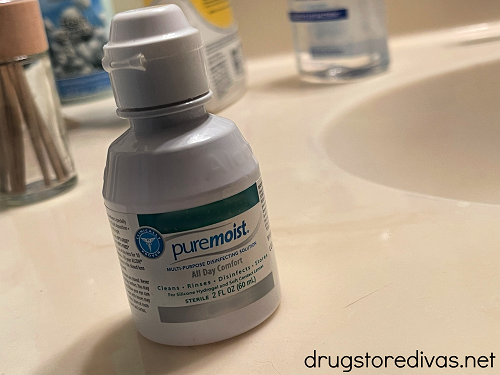 A trial size contact solution on a bathroom counter.