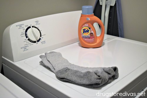 Socks on a dryer with a bottle of detergent behind it.