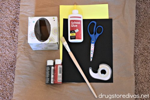 A tissue box, glue, card stock, scissors, tape, paint, and a paint brush.
