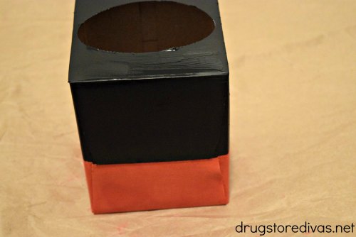 A tissue box with the bottom painted red and the top painted black.