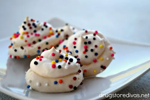 White meringue cookies with sprinkles on a plate.