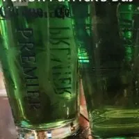 Three green beers on a bar with the words 