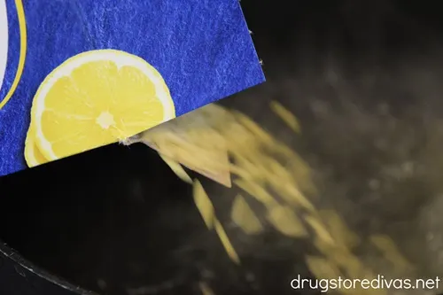 Orzo being poured from a box into a pot of water.