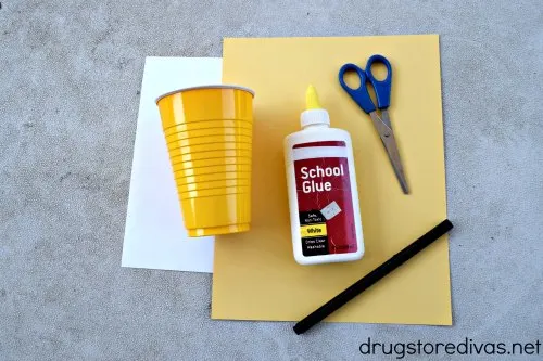 White card stock, yellow card stock, a yellow Solo cup, glue, scissors, and a black marker.