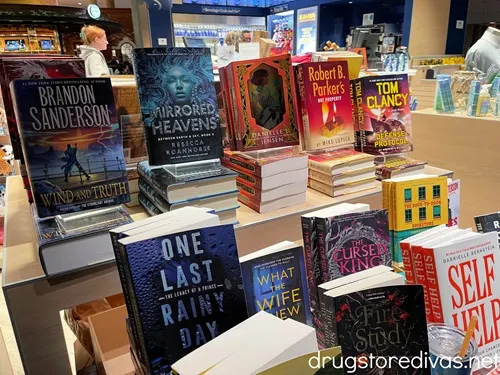 A bunch of books on shelves on sale at a store in an airport.