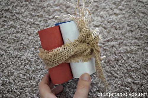 Three toilet paper rolls painted patriotically and wrapped in twine. 