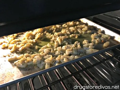 Raw diced potatoes on a baking pan in the oven.