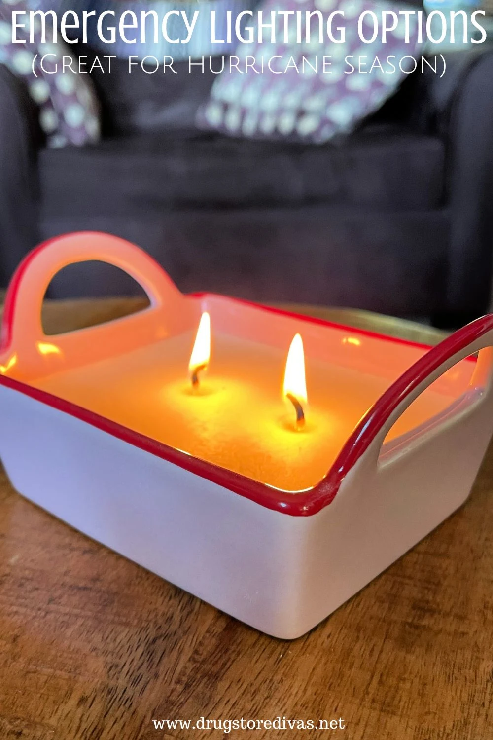 A pink two wick candle with handles on wood table in front of a couch with the words 