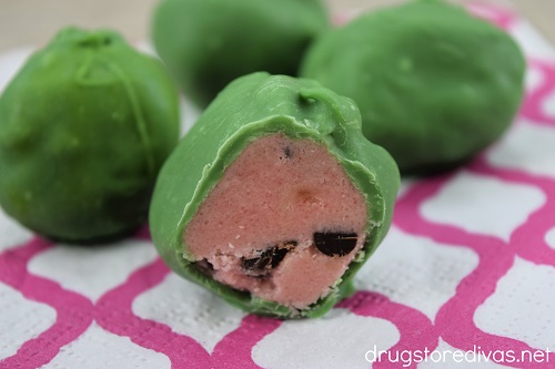 Four watermelon cake pops on a napkin with one cut open to show the inside.