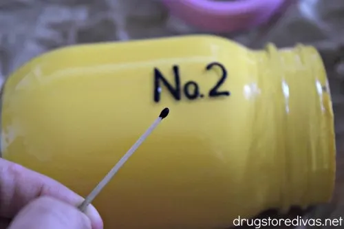 A mason jar painted yellow with "No. 2" painted black on it.