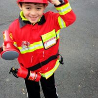 A little boy dressed like a fireman with the words 