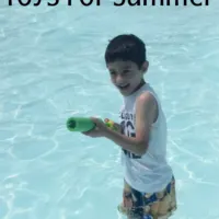A little boy playing with a squirt gun in a pool with the words 
