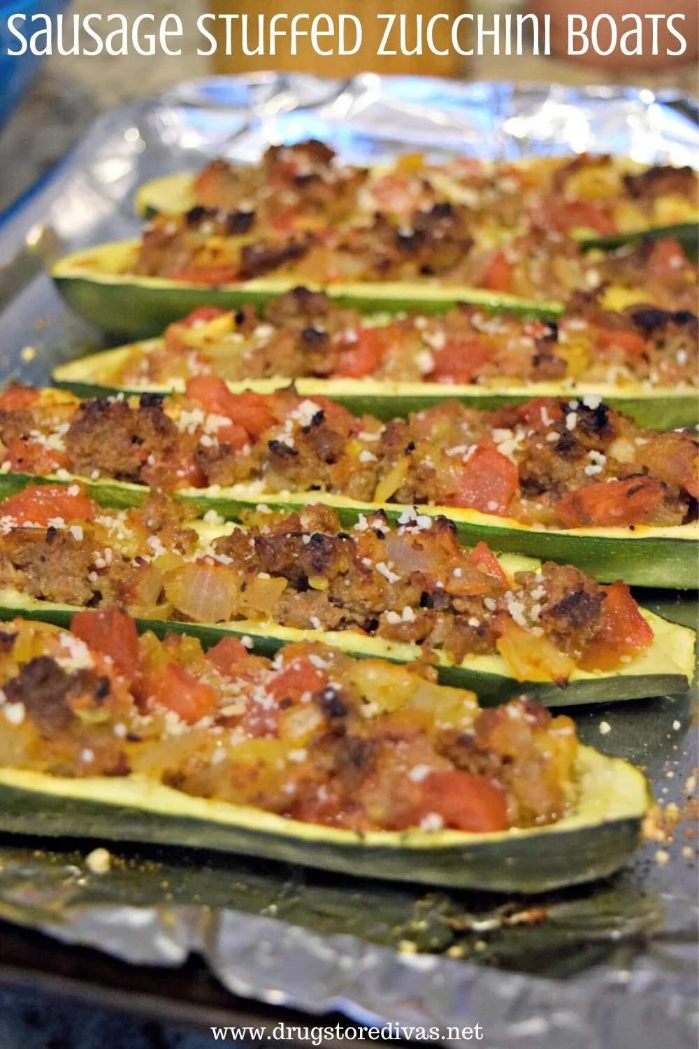 Zucchini boats stuffed with sausage, tomatoes, and onions with the words "Sausage Stuffed Zucchini Boats" digitally written on top.