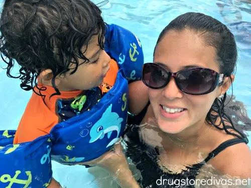 A boy in a lifejacket held by a woman in sunglasses.