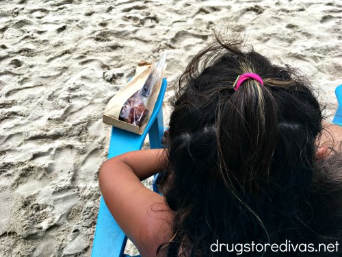 The back of a woman's head who is sitting on a chair on the beach.