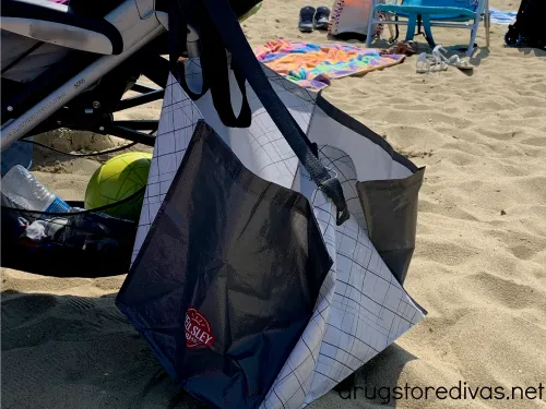 A bag hanging off a stroller at the beach.