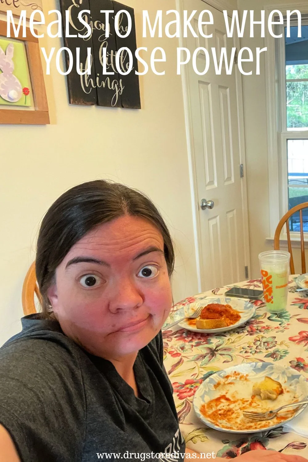 A woman sitting alone at a table with food on it and shrugging with the words 